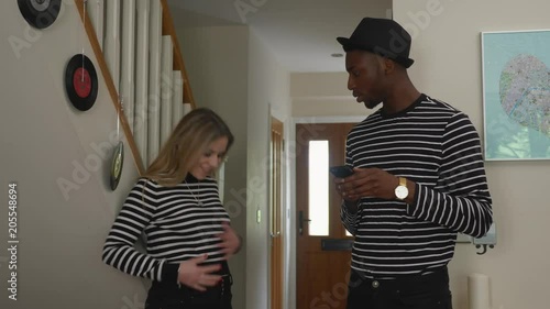 Needy girlfriend wears same outfit as angry man diverse mime. Handheld shot of white girlfriend descending stairs to join black boyfriend and beginning to argue - wearing matching outfits