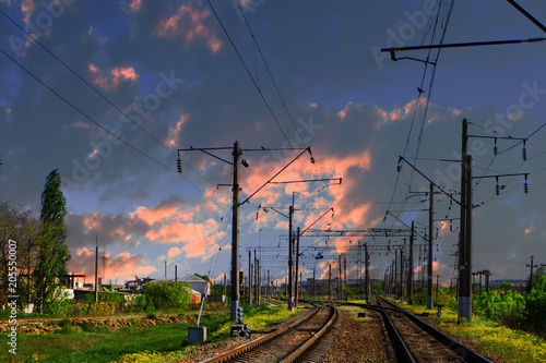 Two lines railway at the country side on the sunset sky background. Electric poles at railroad.