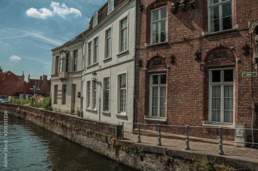 Promenade and old brick buildings on the canal's edge in a sunny day at Bruges. With many canals and old buildings, this graceful town is a World Heritage Site of Unesco. Northwestern Belgium.
