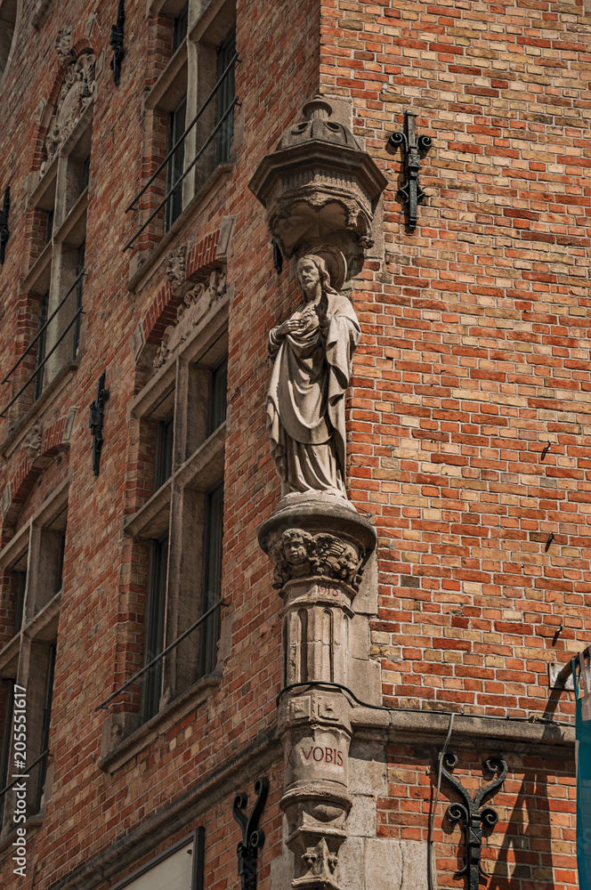 Religious decorative statue of holy at corner of an old brick building in Bruges. With many canals and old buildings, this graceful town is a World Heritage Site of Unesco. Northwestern Belgium