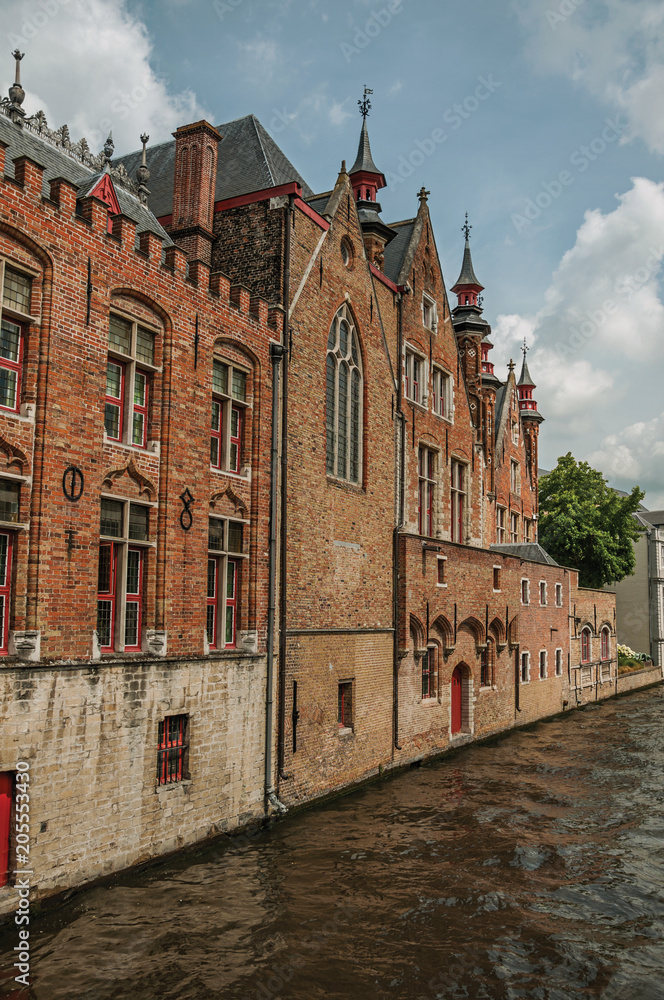 Old brick buildings on the canal's edge in a sunny day at Bruges. With many canals and old buildings, this graceful town is a World Heritage Site of Unesco. Northwestern Belgium.
