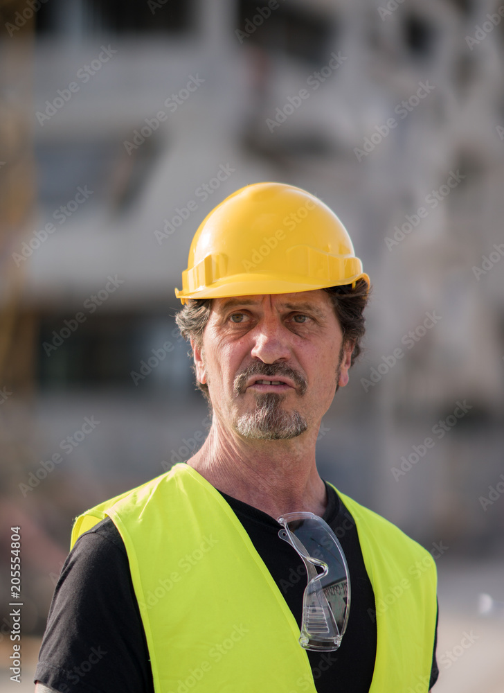 Portrait of a caucasian civil engineer wearing yellow reflective vest and hardhat looking away Portrait of a caucasian civil engineer wearing yellow reflective vest and hardhat looking away