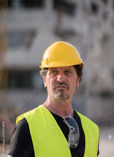 Portrait of a caucasian civil engineer wearing yellow reflective vest and hardhat looking away