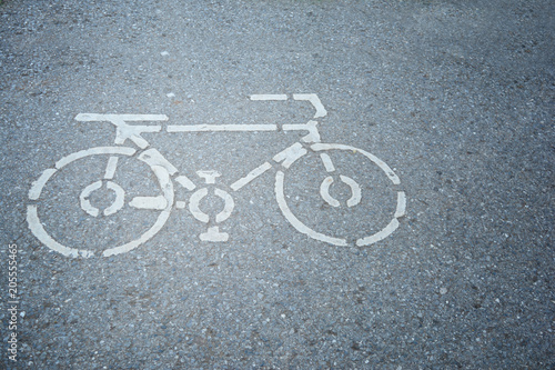 a white sign of bicycle way on the asphalt street at the park in city