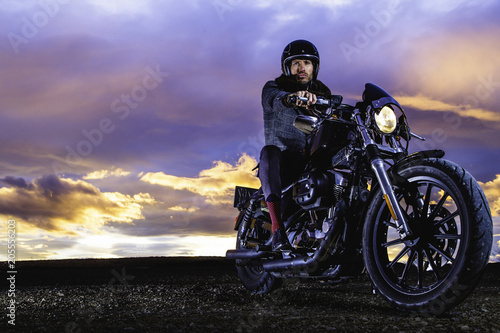 Photo Modern biker sits and ready for shooting on classic motorcycle at closed road