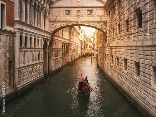 Venecia, Italia. Gondolero llevando en su góndola a turistas, por el puente de los suspiros, durante un atardecer soleada