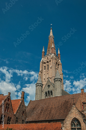 Brick church steeple, roofs and public lamp contrasting with blue sky in Bruges. With many canals and old buildings, this graceful town is a World Heritage Site of Unesco. Northwestern Belgium.