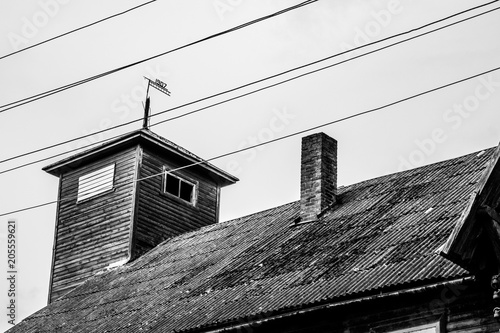 Black and white image of old wooden house, number 1907 is on it's roof top.