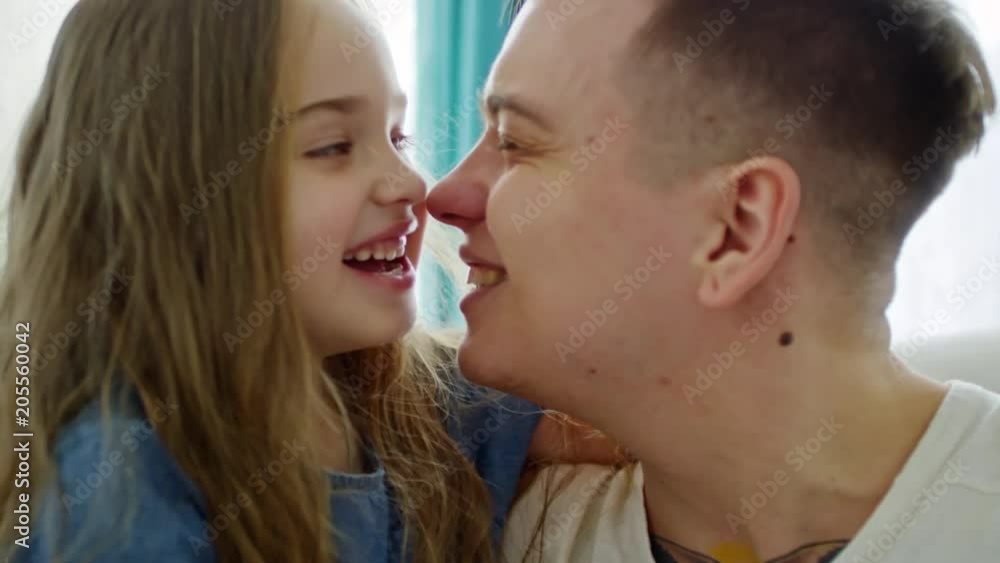 Medium shot of happy young father and cute little girl smiling and touching noses Medium shot of happy young father and cute little girl smiling and touching noses