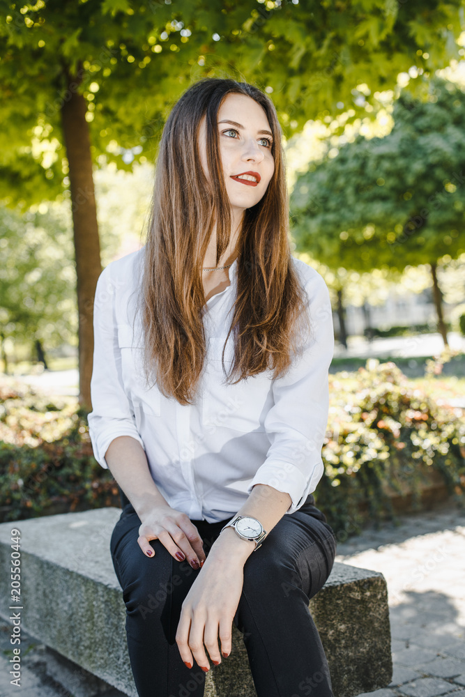 Young woman resting in the park. Female portrait. The girl smiles. Lady with long and loose hair. Young woman resting in the park. Female portrait. The girl smiles. Lady with long and loose hair.