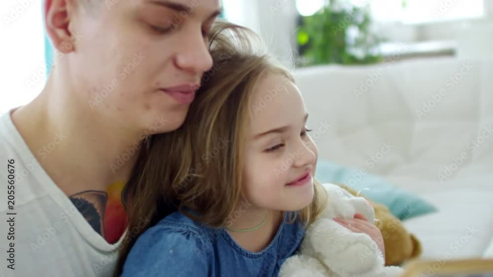 Medium shot of young father reading book to cute little girl with plush toy Medium shot of young father reading book to cute little girl with plush toy