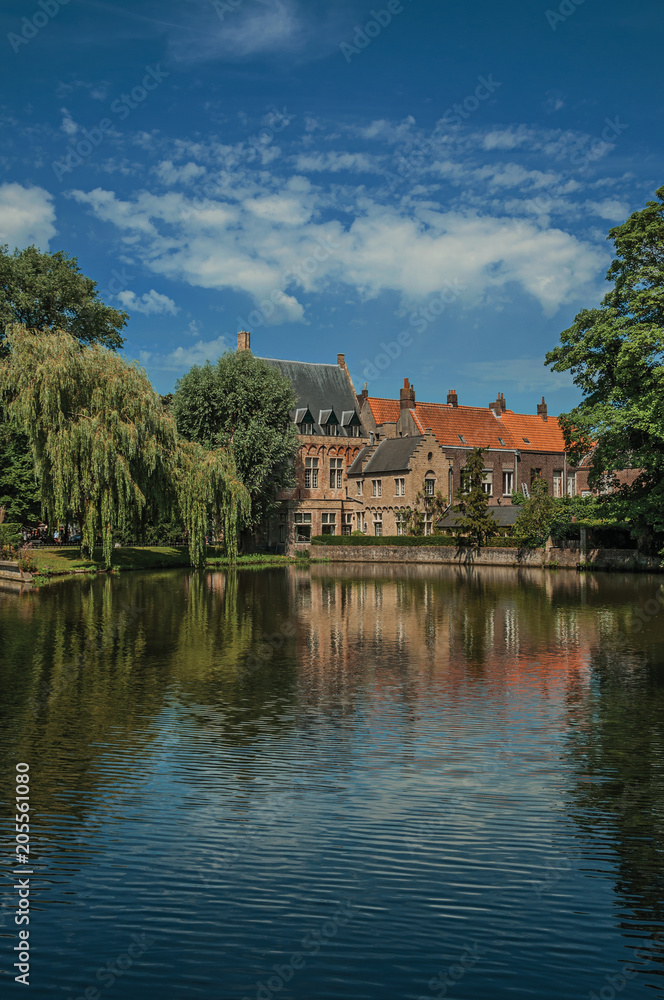 Amazing lake surrounded by greenery and old brick building on the other side in Bruges. With many canals and old buildings, this graceful town is a World Heritage Site of Unesco. Northwestern Belgium.