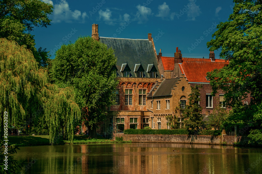Amazing lake surrounded by greenery and old brick building in Bruges. With many canals and old buildings, this graceful town is a World Heritage Site of Unesco. Northwestern Belgium. Retouched photo.