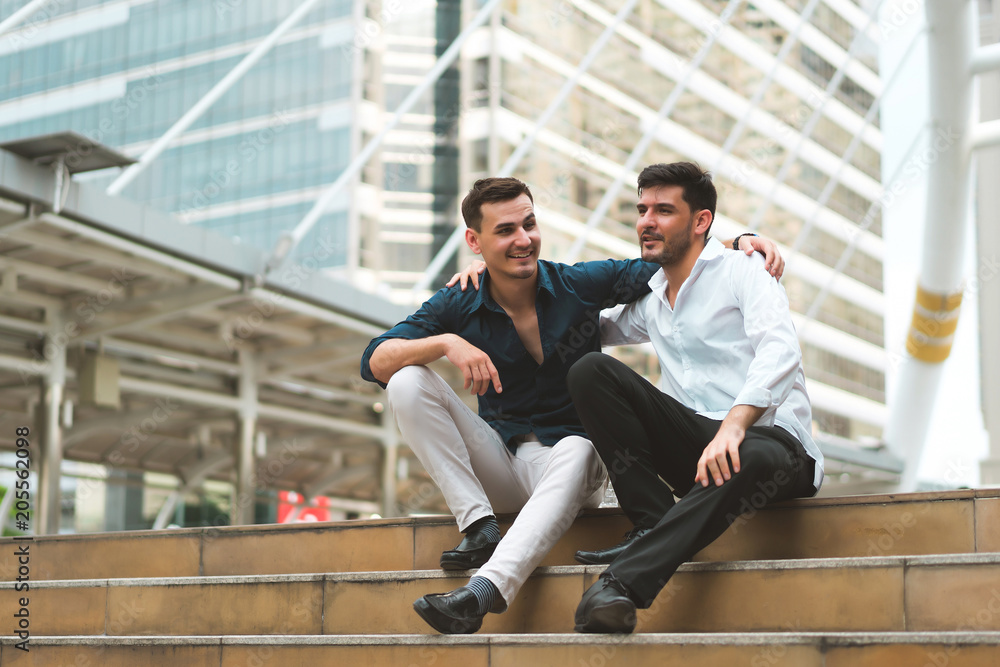 Two friend sitting down on stairs shaking hands. Businessmen very happy after success project. concept of business marketing, negotiation, compliment and management. Two friend sitting down on stairs shaking hands. Businessmen very happy after success project. concept of business marketing, negotiation, compliment and management.
