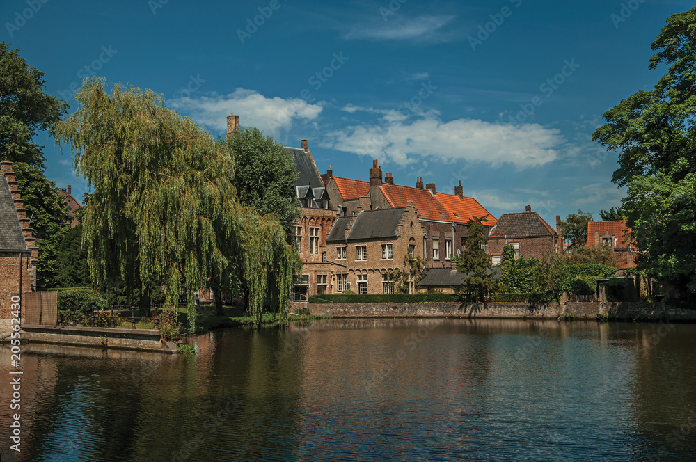 Amazing lake surrounded by greenery and old brick building on the other side in Bruges. With many canals and old buildings, this graceful town is a World Heritage Site of Unesco. Northwestern Belgium.