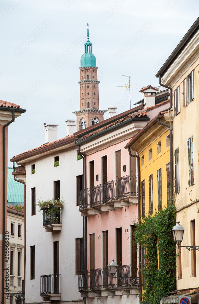 Fototapeta premium Bottom perspective of the famous Clock Tower of Vicenza seen from one of the town streets with some old palaces in the foreground