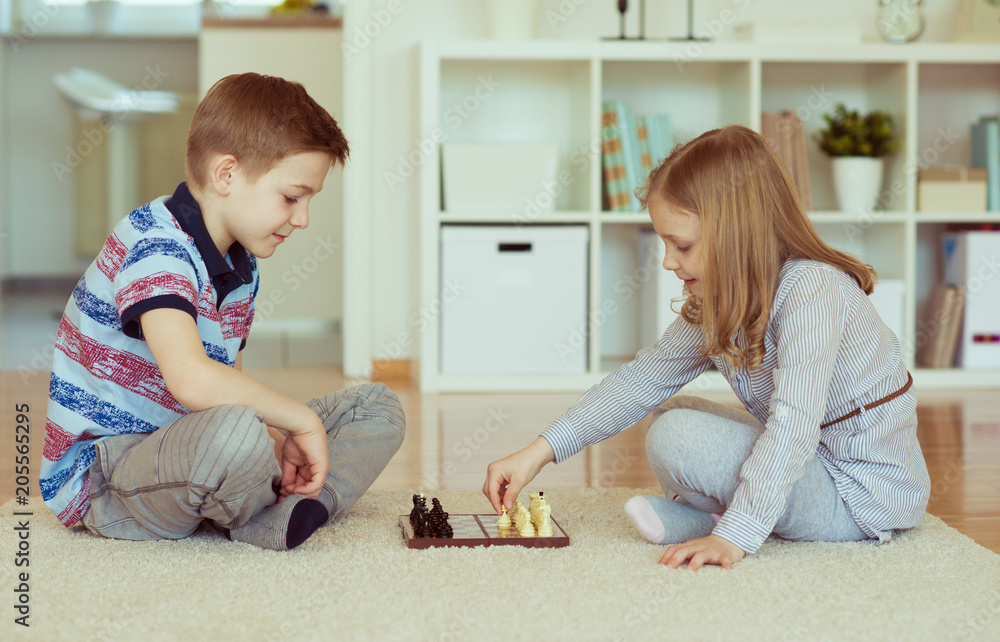 Naklejka premium Two little children playing chess at home