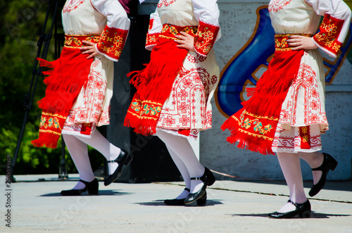 People in Bulgarian costumes with red colors dancing a traditional dance