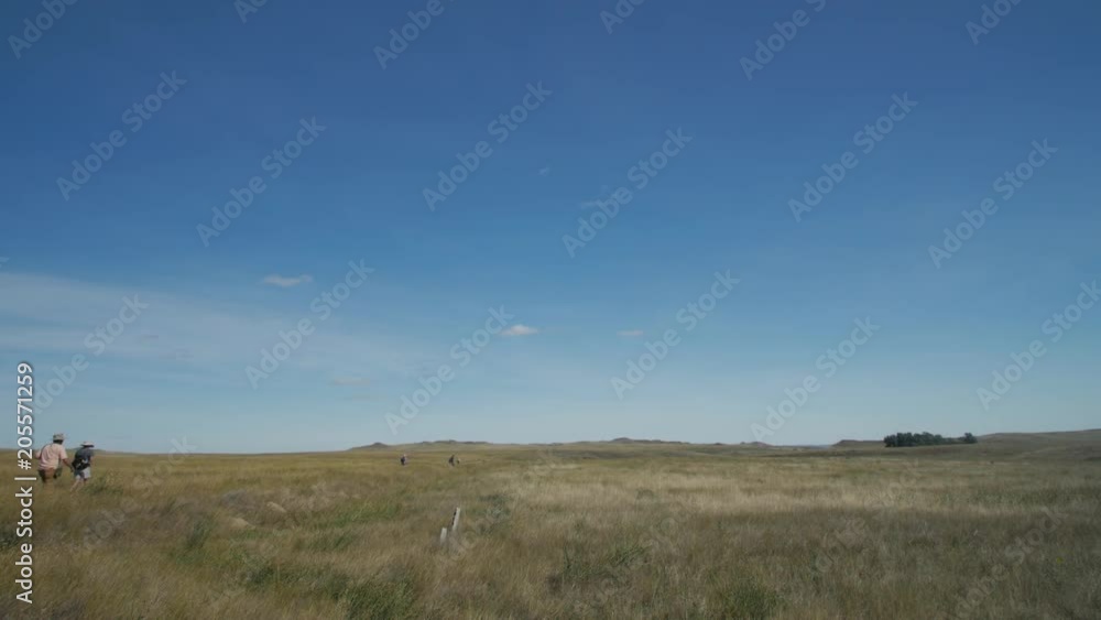 Hikers make way through prairie grasslands at noon Hikers make way through prairie grasslands at noon