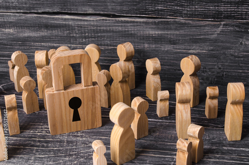 A crowd of people stands and looks at the padlock in the center. The issue is safe and secure in society. Preservation of property and citizens, observance of the law. Concept of the law. photo