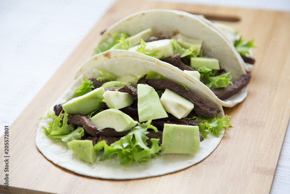 Mexican food. Carnitas street tacos in corn tortillas on wooden board. Side view.