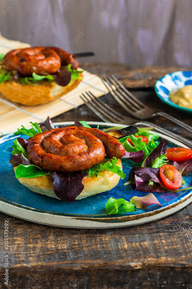 Chilli pork pinwheel sausages on a bun with fresh green leaf lettuce salad