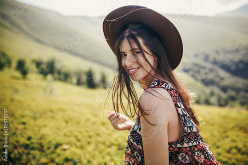 happy traveler hipster girl in hat, walking in sunny mountains. summer vacation. space for text. happy atmospheric moment. focus on hair. travel and wanderlust concept