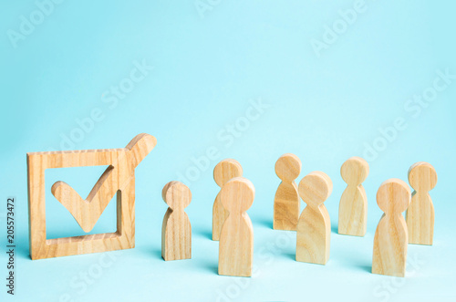 human figures stand together next to a tick in the box. The concept of elections and social technologies. Volunteers, parties, candidates, constituency electorates. Human rights. Selective focus