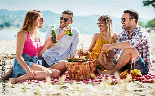 Group of friends enjoying picnic on the beach. Lifestyle, vacation, relationships concept © bobex73