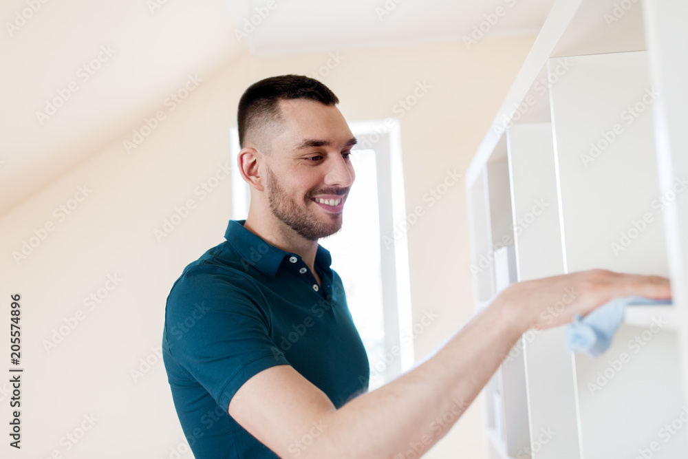 household, cleaning and people concept - man wiping shelf with cloth at home