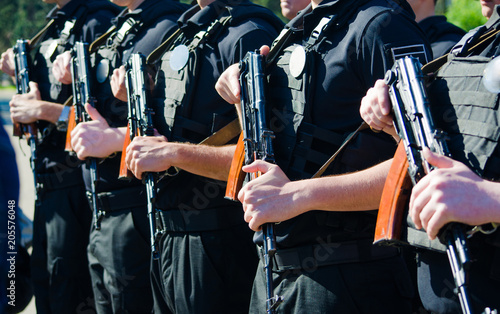 Police officers in black uniform standing in a row with big weapons. Concept of protecting the city