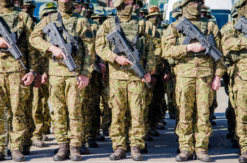 Soldiers in military uniform and in masks standing in a row with guns in their hands