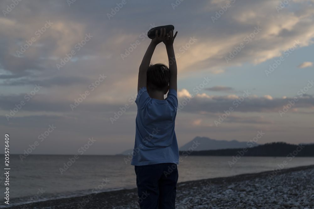 Fototapeta premium boy is holding the stone on the beach