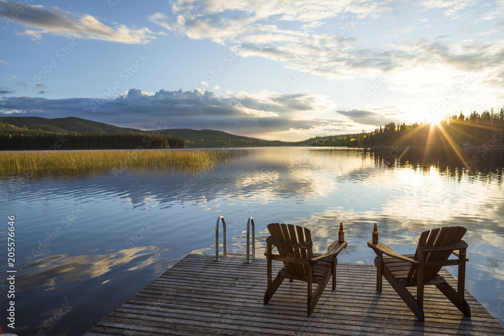 Empty chairs on wooden pier over lake against cloudy sky during sunset Empty chairs on wooden pier over lake against cloudy sky during sunset
