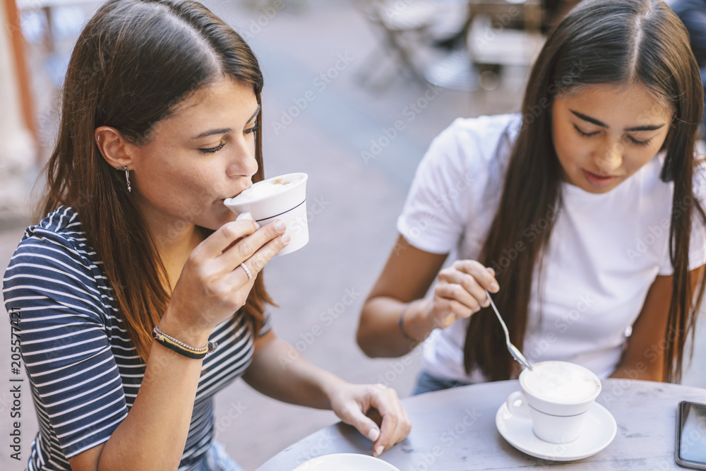 High angle view of friends drinking cappuccino while sitting at sidewalk cafe High angle view of friends drinking cappuccino while sitting at sidewalk cafe