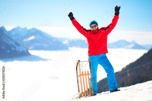 Young attractive man ready to go sledding in Swiss Alps during winter vacation.
