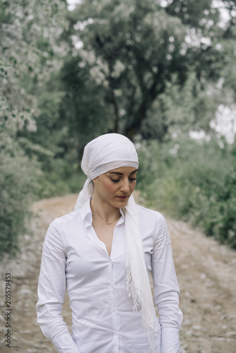 woman with white headscarf in the forest, has cancer © karrastock