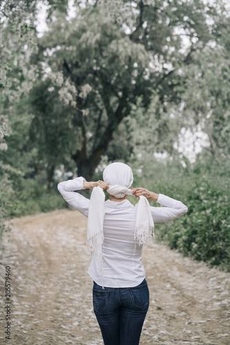 woman with white headscarf in the forest, has cancer © karrastock