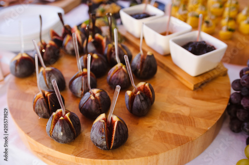 Tapas on wooden plate: figs, cheese, nuts, honey. Drink reception. photo