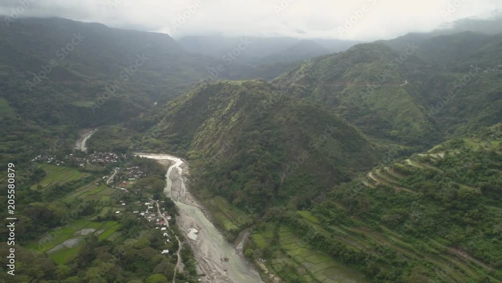 Aerial view of mountain valley with river, rice terraces, farmland in the Philippines, Luzon. Aerial view of mountains covered forest, tree. Cordillera region. Aerial view of mountain valley with river, rice terraces, farmland in the Philippines, Luzon. Aerial view of mountains covered forest, tree. Cordillera region.