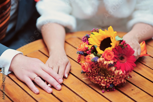 Autumn wedding bouquet and hands of beautiful wedding couple. Love and tenderness concept close up photo with selective focus