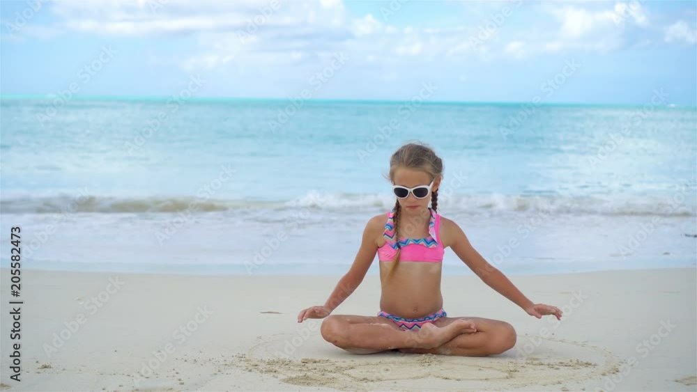 Adorable little girl lying on white sandy beach Adorable little girl lying on white sandy beach
