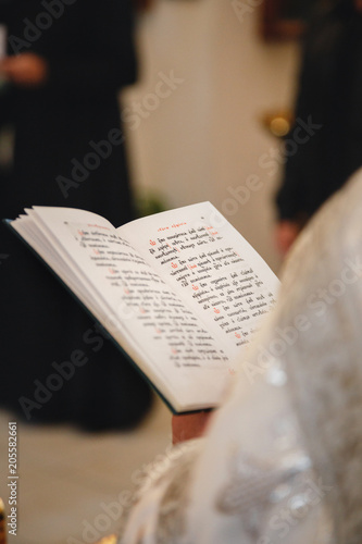 Christening in the church, priest is reading a prayer from the Bible. Details in the orthodox christian church