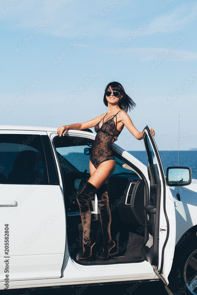 Sexy girl in lingerie stands on a white car with an open door on a  background of water and sky Photos | Adobe Stock