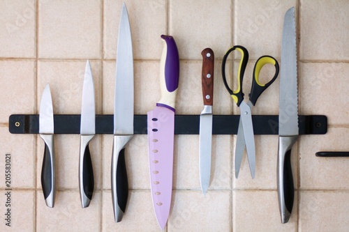 set of kitchen knives on a magnetic strip on the tile wall