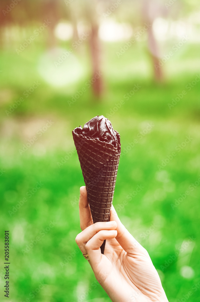 the girl is holding a black ice cream. waffle black. filter. sunny day . summer. the girl is holding a black ice cream. waffle black. filter. sunny day . summer.