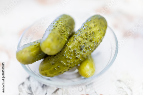 Macro closeup of traditional Russian or Ukrainian juicy kosher Jewish green pickles in bowl as appetizer  side dish on table