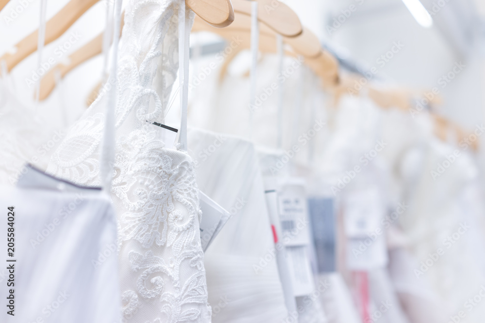 Many wedding dresses with price tags in boutique discount store