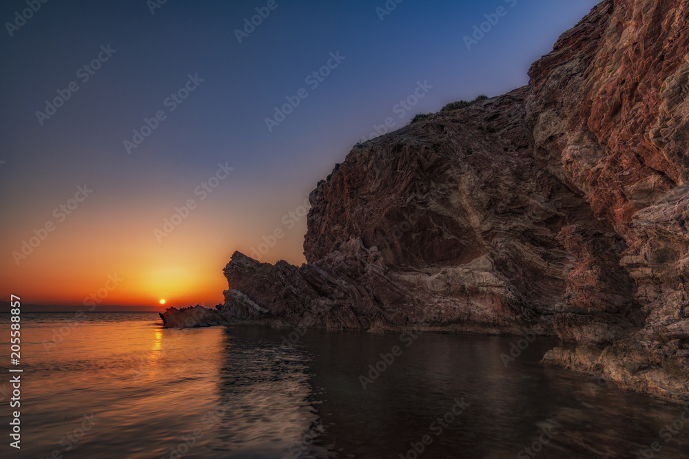 Sole che tramonta dietro la scogliera di Cala Rossa, Terrasini - provincia di Palermo IT	