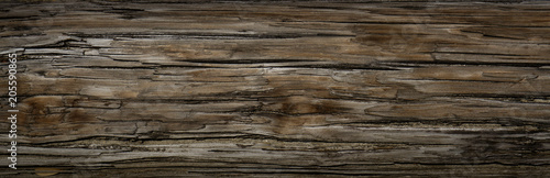 Old Dark rough wood floor or surface with splinters and knots. Square background with flooring or boards with wood grain. Old aged timber in a barn or old house.